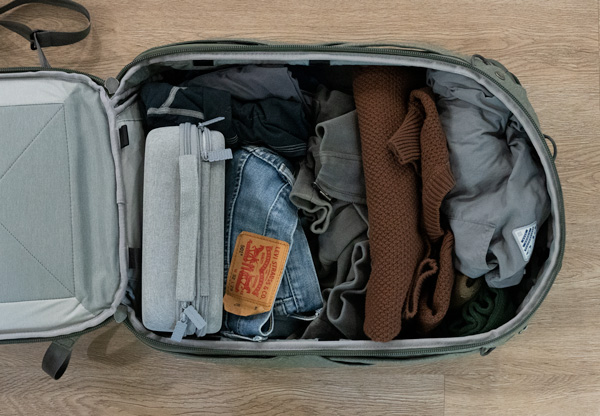 top down shot of an open travel backpack full of clothes and a hard sided dopp kit