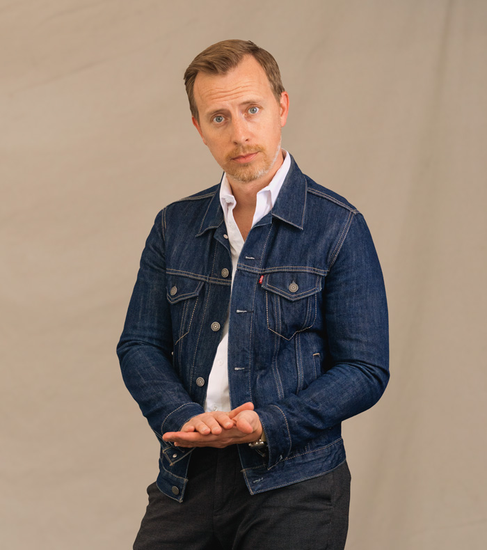 andrew wearing a dark blue denim trucker jacket from levi's with a white dress shirt