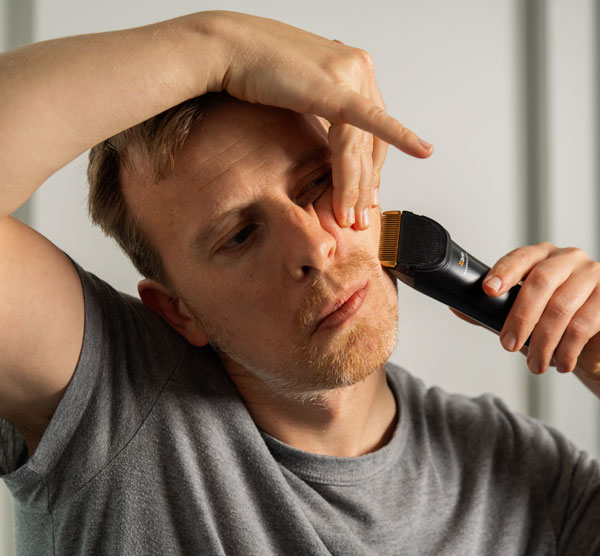 man pulling up on his cheek skin and shaving his cheek line