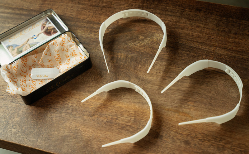 3 slick collars of different sizes sitting next to its packaging