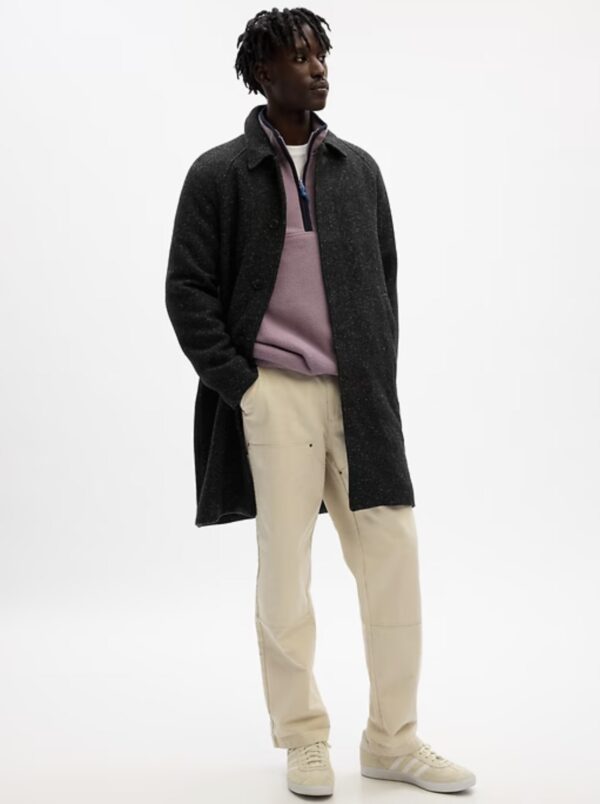 a man wearing a wool car coat over a sweater and chino pants