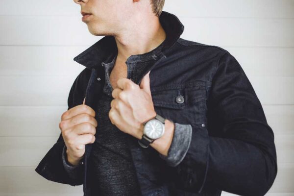 a man wearing a black denim jean jacket over a henley shirt