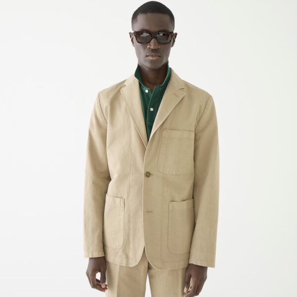 a man wearing a chino suit jacket over a dress shirt and accessorized with sunglasses