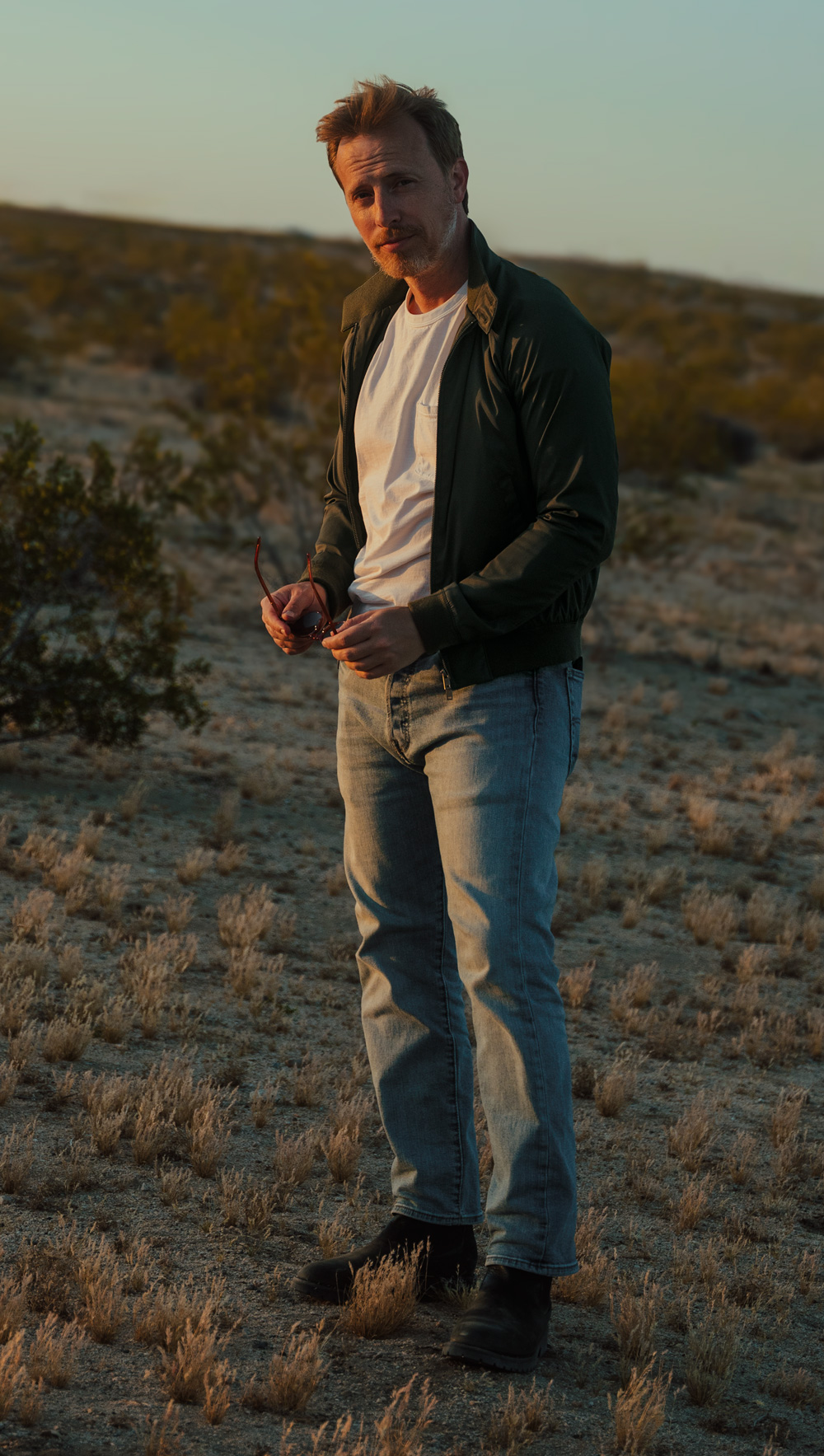 man wearing a navy harrington jacket at the beach