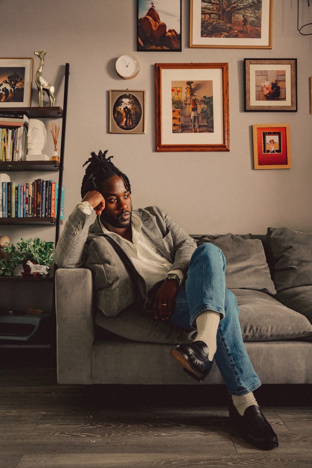man sitting on a couch wearing light wash denim with a blazer and linen shirt