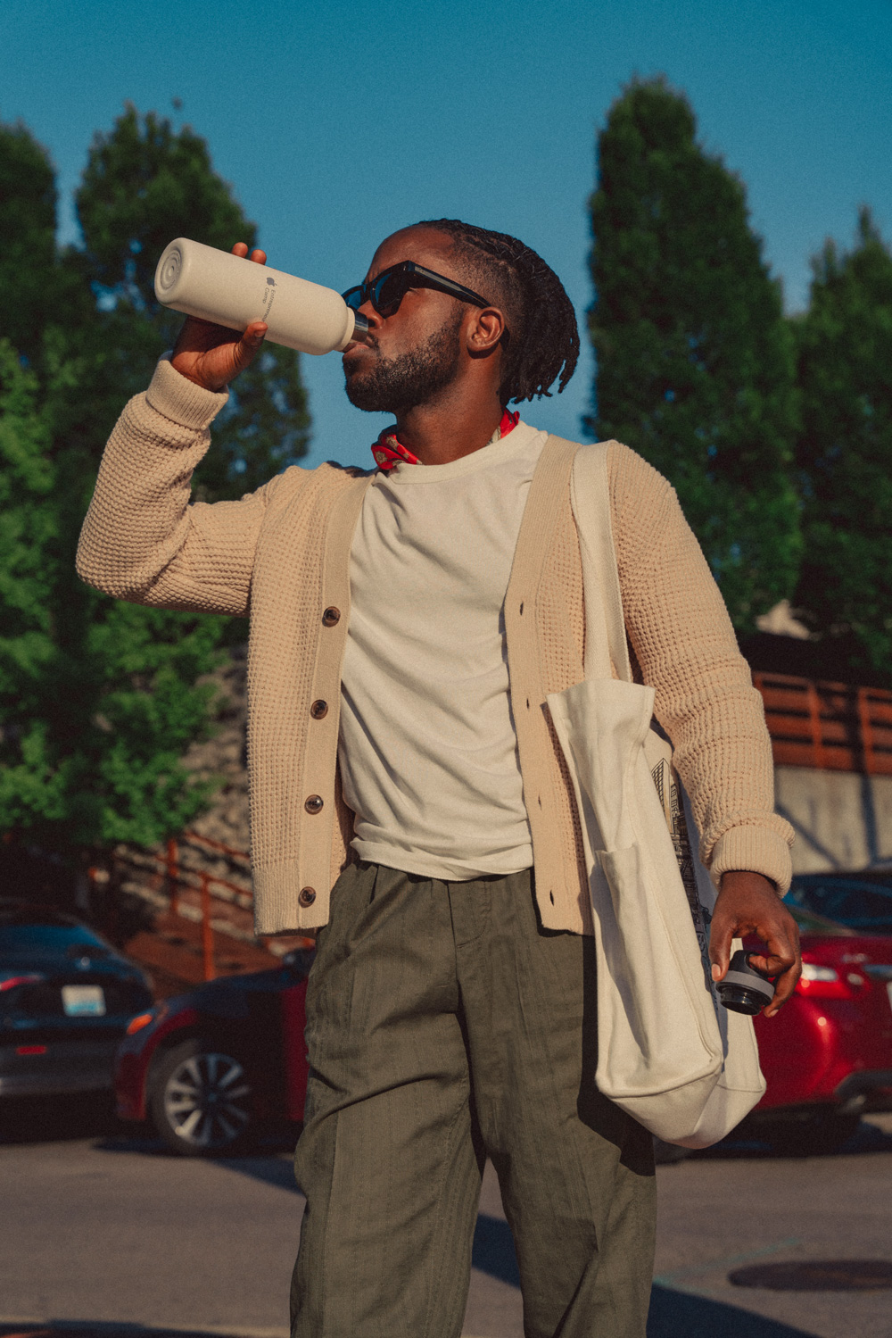 Daniel in linen pants and white tshirt, drinking from a water bottle