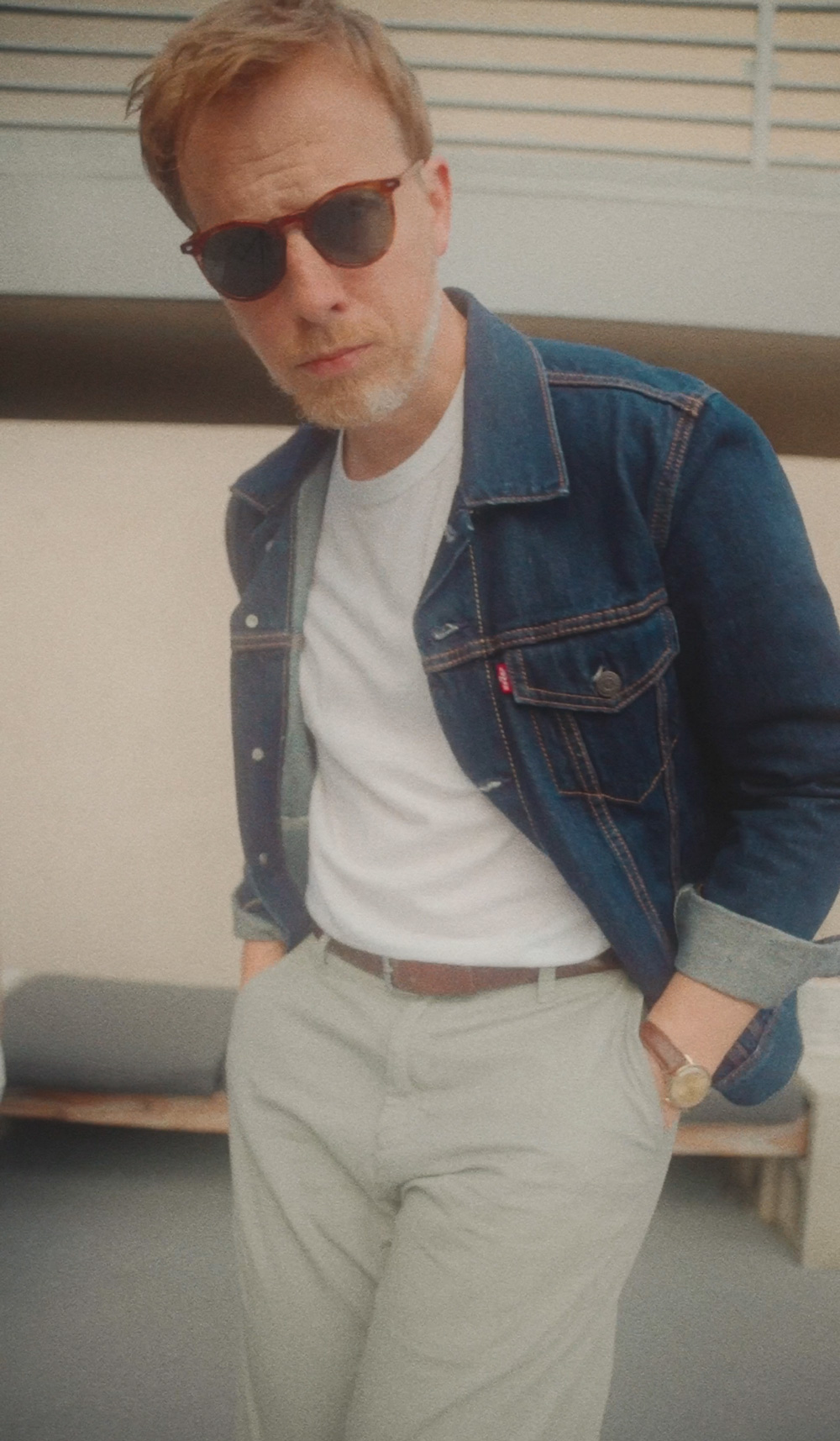 close up of man wearing denim jacket, white t-shirt, chino pants
