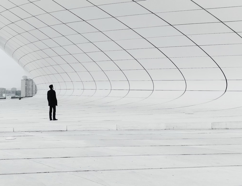 black and white photo of man staring at patterned architecture