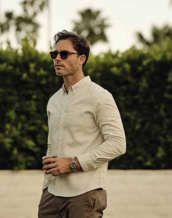 a man wearing a long sleeve linen button up shirt and sunglasses