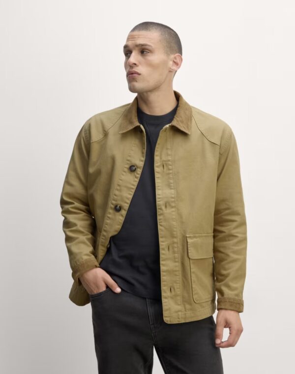 a man wearing a barn style work jacket over a shirt and pants