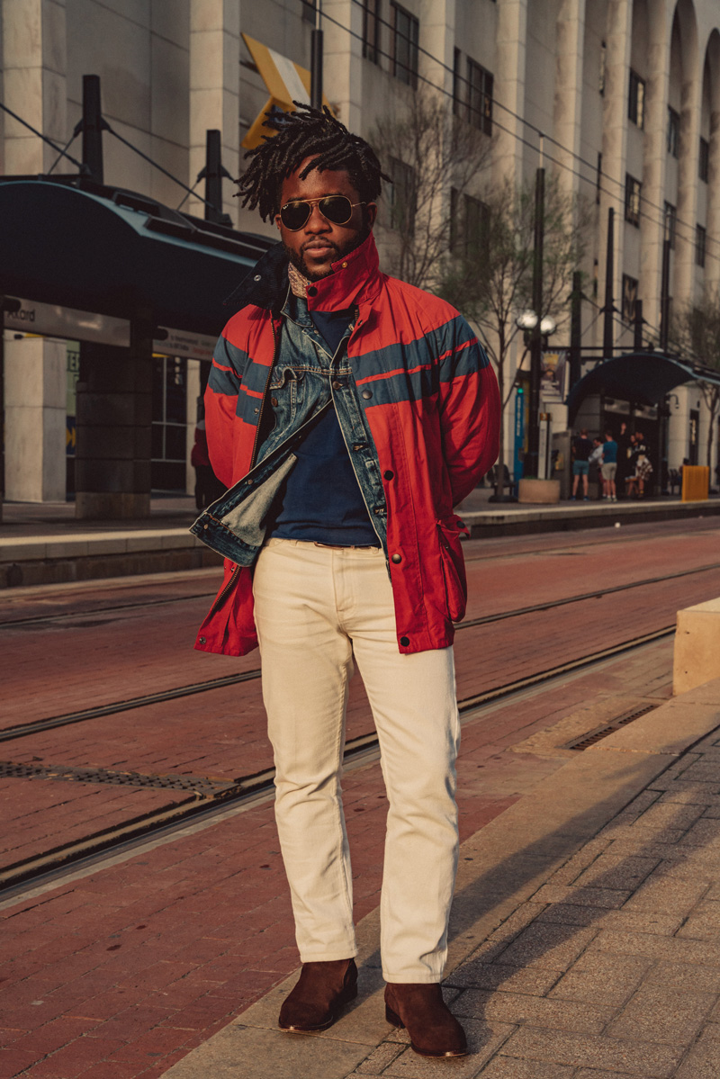 red rain coat over a medium blue jean jacket and a blue sweater with white jeans