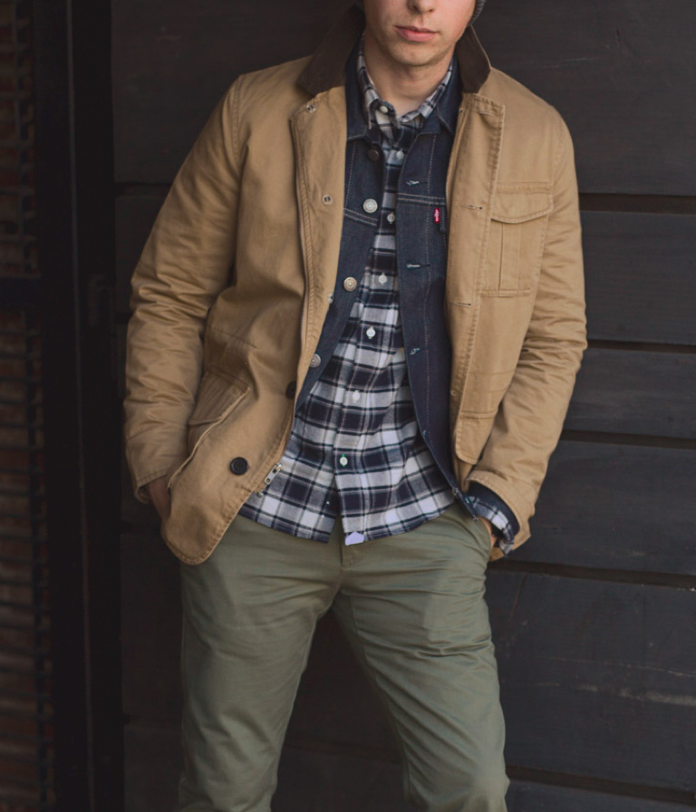 close up of tan field coat with denim jacket and plat flaneel shirt