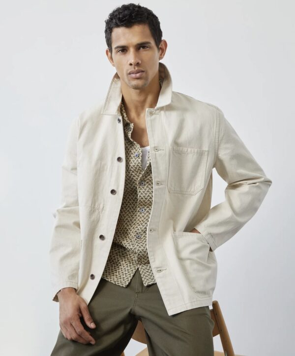 a man wearing a Japanese selvedge material chore style coat over a button up shirt and pants