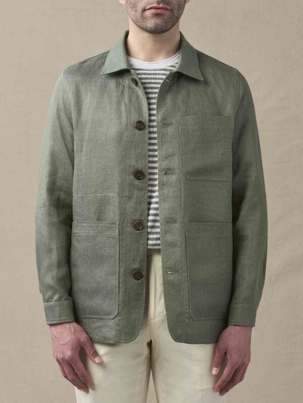 a man wearing a green chore coat over a striped shirt and chino pants