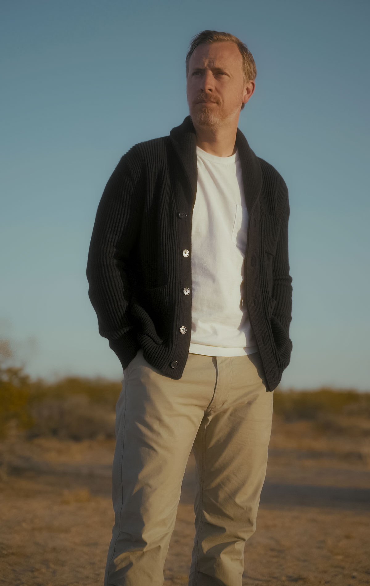 men's fall outfit with black shawl collar cardigan, white pocket t-shirt, and tan chinos