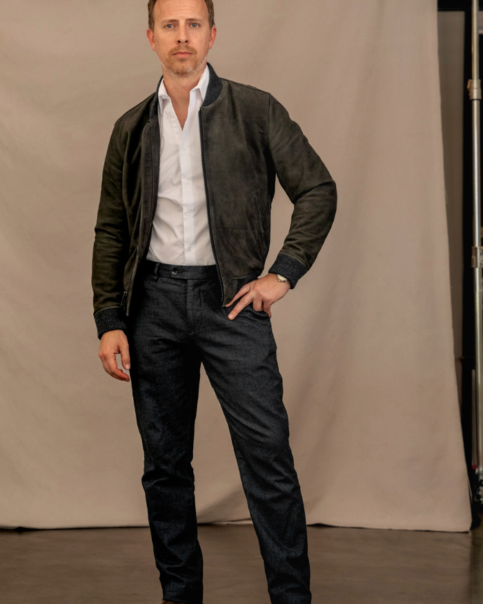 a man wearing a leather jacket over a dress shirt and dress pants