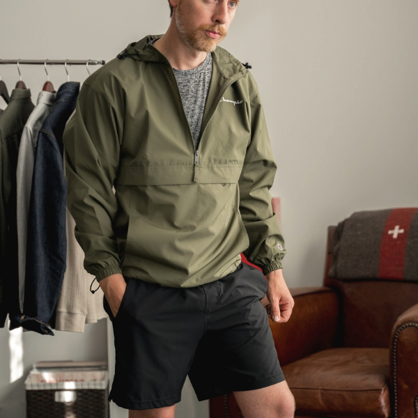 a man wearing a wind and water resistant wind breaker jacket over a crew neck shirt and casual shorts