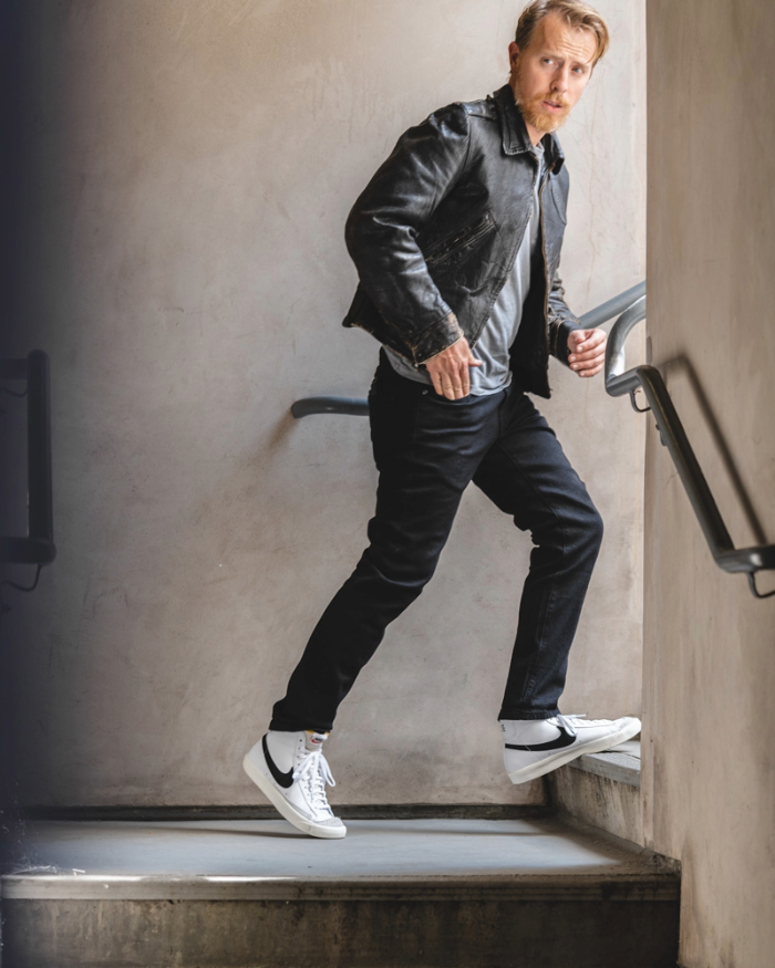 a man wearing nike blazer mid high top sneaker with slim jeans, leather jacket, and a casual shirt