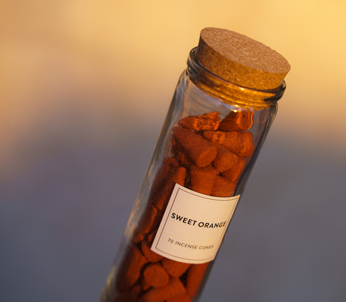 a glass bottle with a cork stopper that is filled with sweet orange scented incense cones