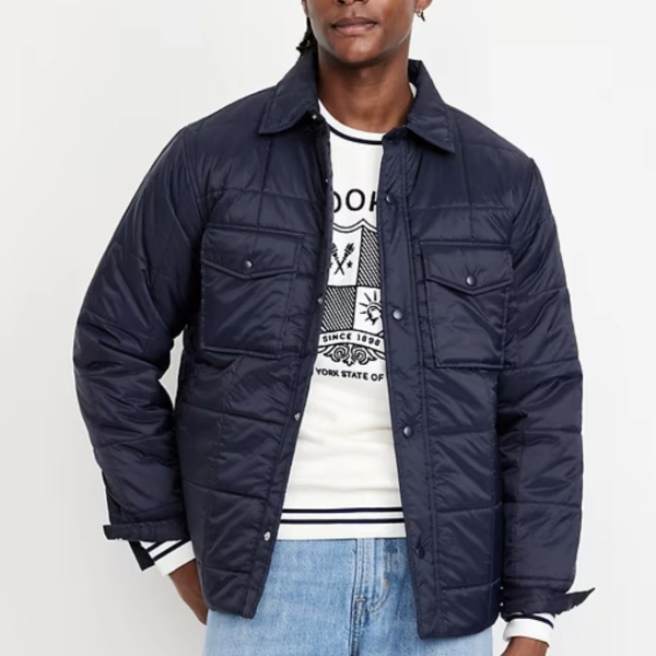a man wearing a quilted jacket over a graphic shirt