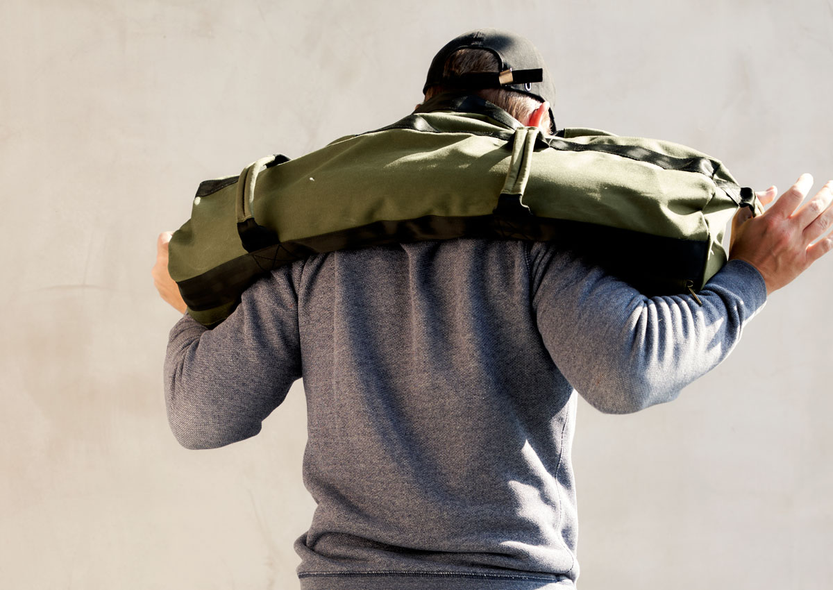 man squatting with a workout sandbag