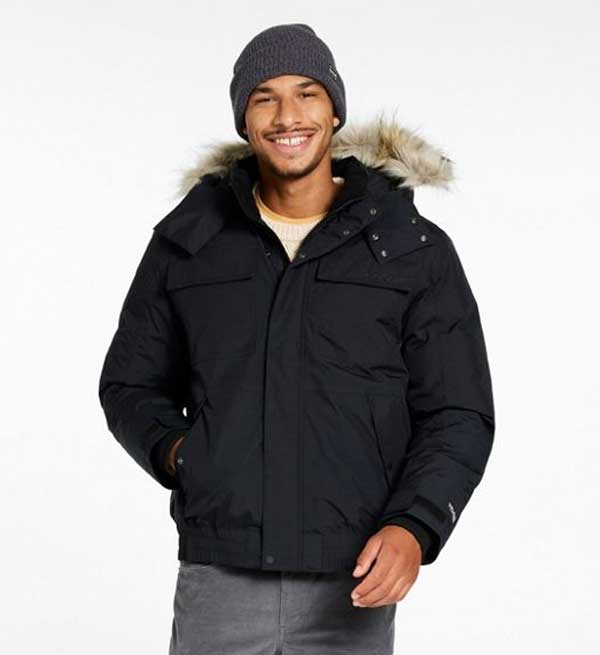 man wearing a waist-length black winter coat with brown fur lined hood