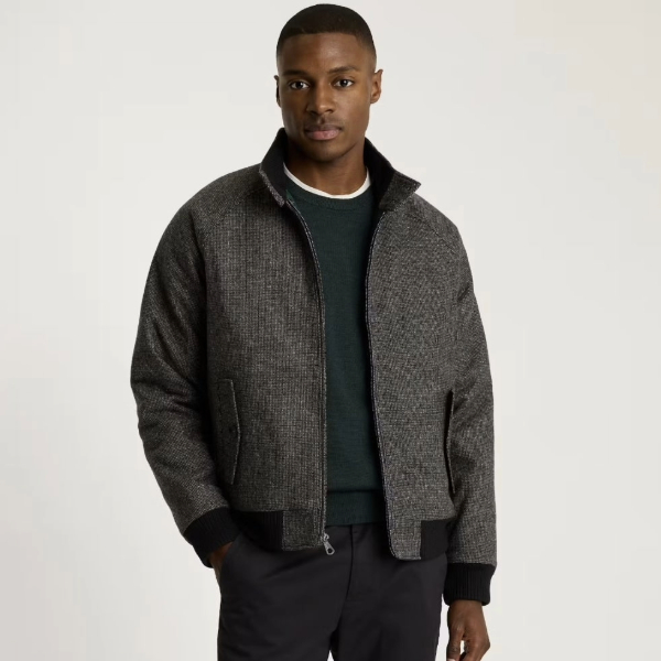 a man wearing a zip front wool harrington style jacket over a sweater and pants