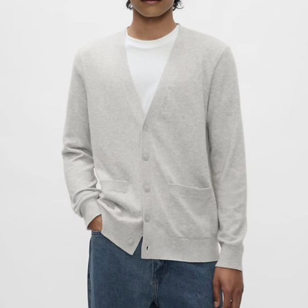 a man wearing a long sleeve v neck cardigan sweater over a crew neck shirt and denim jeans