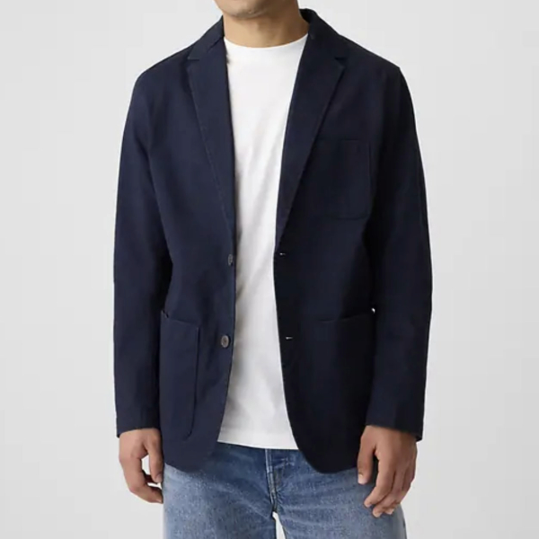 man wearing a navy twill blazer over a crew neck shirt and denim jeans