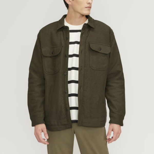 a man wearing an unbuttoned overshirt over a striped crewneck shirt and casual pants