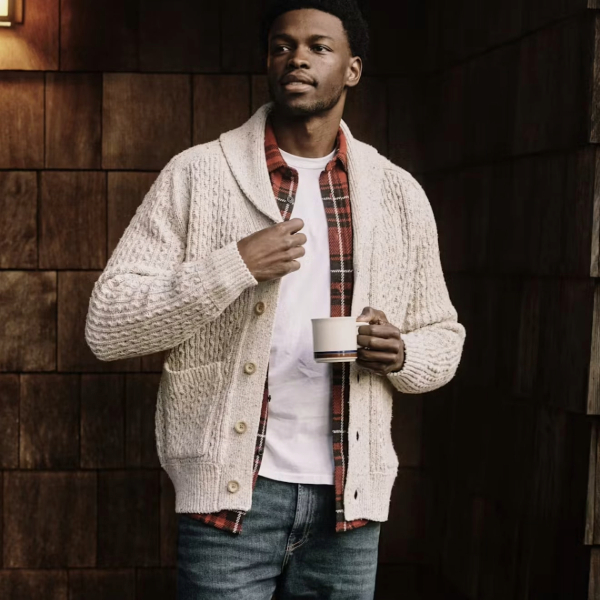 a man wearing a shawl collar style cardigan over a shirt and denim jeans