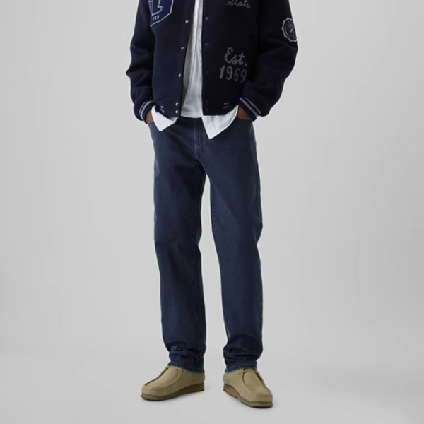 a man wearing straight fit denim jeans with lace up boots and a zip front jacket