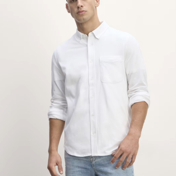 a man wearing a long sleeve button front shirt with rolled sleeves and with denim jean pant