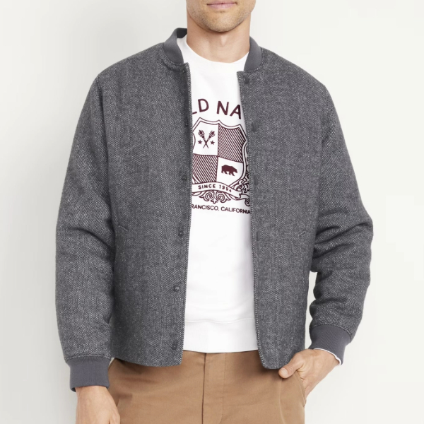 man wearing a zip front tweed bomber jacket over a graphic shirt and pants