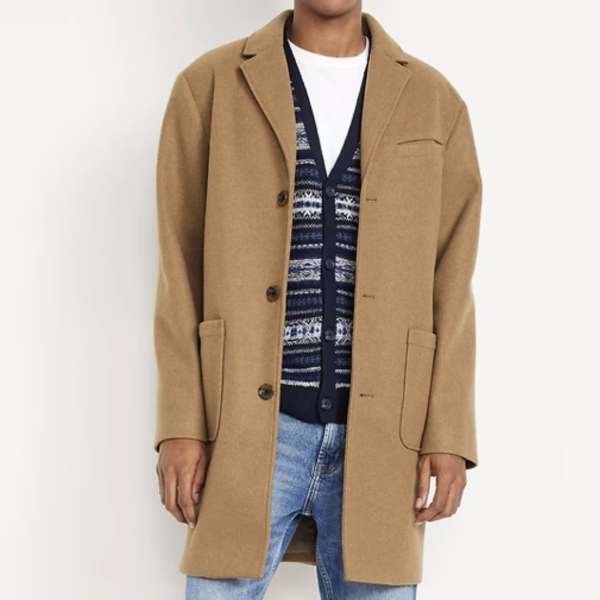 a man wearing a topcoat over a shirt and v neck cardigan and denim jeans