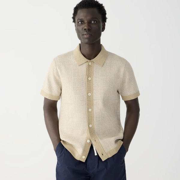 a man wearing a jaquard knit sweater short sleeve polo shirt over pants