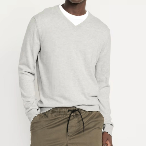 man wearing a v neck sweater over a crew neck shirt and casual pants