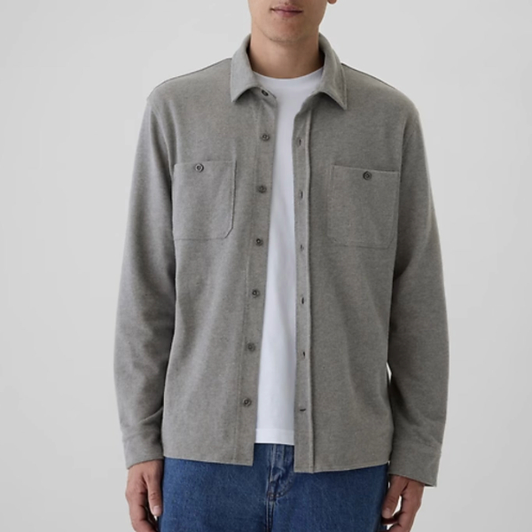 a man wearing a long sleeve button front jersey shirt over a crew neck shirt and denim jeans