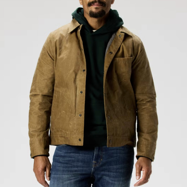 man wearing a waxed snap jacket over a hooded sweater and denim pants