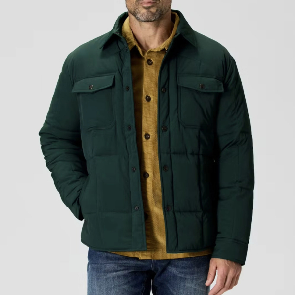 man wearing a quilted style jacker over a button down shirt and denim pants