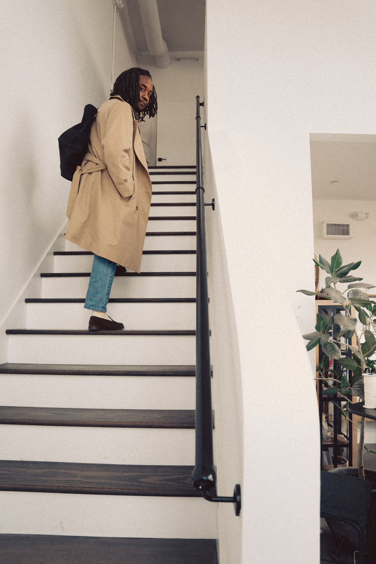 daniel in a trench coat walking up stairs