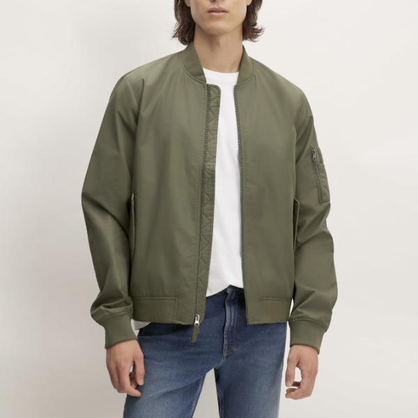 man wearing bomber jacket over a crew neck shirt and denim jeans