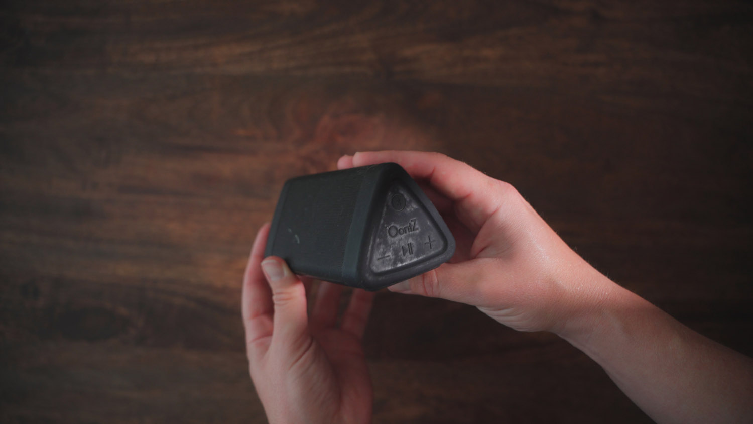 a person showing a close up of a blue tooth speaker device