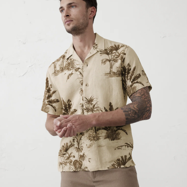 man wearing a short sleeve button front resort style shirt with palm tree print