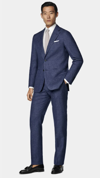 man wearing a blue suit with a dress shirt and tie and dress shoes