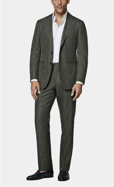 man wearing a tailored dark green suit with a white dress shirt and dress shoes