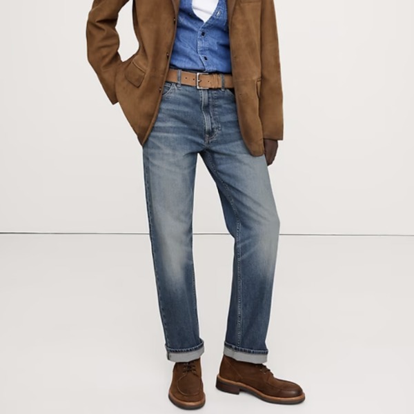 man wearing medium wash straight fit denim jeans with a coat and suede shoes
