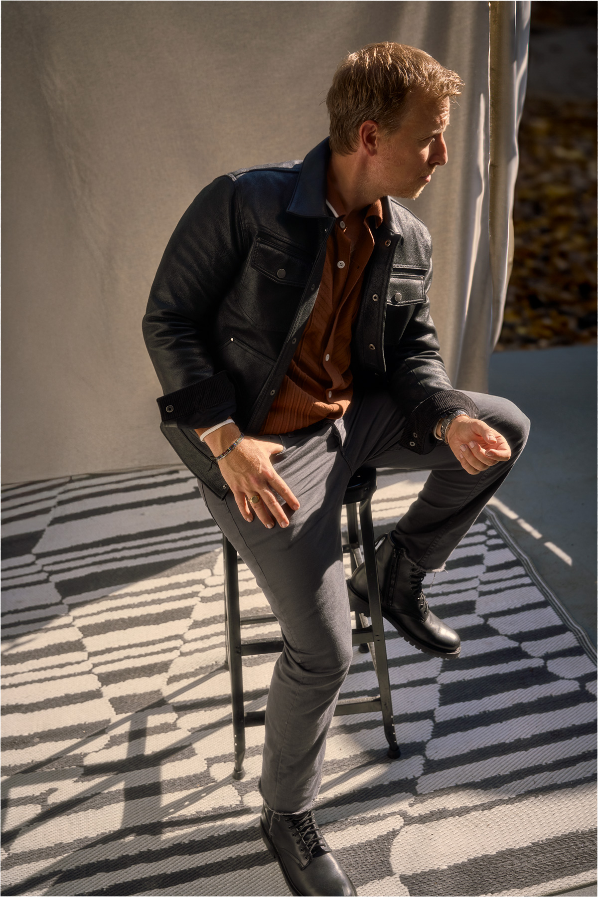 black leather jacket over a sweater polo with grey twill pants and black boots