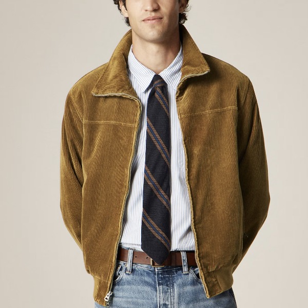 man wearing a corduroy zip front jacket with a button front shirt and tie and denim jeans