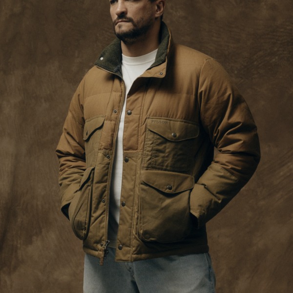 man wearing a waxed down cruiser style jacket over a shirt and jeans